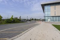 the sidewalk is empty outside of a building and some grass in front of it's entrance