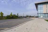 the sidewalk is empty outside of a building and some grass in front of it's entrance