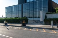 a empty street with trash cans in a building next to it and a yellow line on the curb