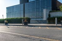 a empty street with trash cans in a building next to it and a yellow line on the curb