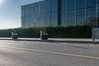 a empty street with trash cans in a building next to it and a yellow line on the curb