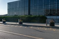 a empty street with trash cans in a building next to it and a yellow line on the curb