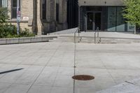 a sidewalk in front of a building with stairs up to the top of it,