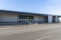 a long building that is built into the side of the road by the street, with a blue sky