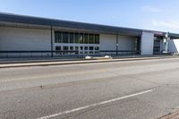 a long building that is built into the side of the road by the street, with a blue sky