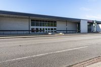 a long building that is built into the side of the road by the street, with a blue sky