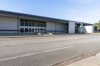 a long building that is built into the side of the road by the street, with a blue sky