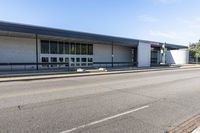 a long building that is built into the side of the road by the street, with a blue sky