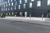 black car parked in front of black and grey building in front of parking spaces and building