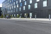 black car parked in front of black and grey building in front of parking spaces and building