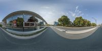 a view looking at an intersection of trees and buildings from the road and skateboarder