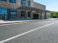 a sidewalk that has a sidewalk sign on it that says green lane park school, in the middle of the street are two buildings with windows and three storys with a sky background