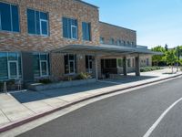 a sidewalk that has a sidewalk sign on it that says green lane park school, in the middle of the street are two buildings with windows and three storys with a sky background