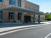 a sidewalk that has a sidewalk sign on it that says green lane park school, in the middle of the street are two buildings with windows and three storys with a sky background