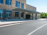 a sidewalk that has a sidewalk sign on it that says green lane park school, in the middle of the street are two buildings with windows and three storys with a sky background