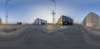 the panorama lens image shows a curved street with multiple buildings and telephone poles with power lines in front