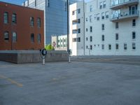 a street with a building near the building in the middle and on the left of which is a parking lot, as shown in this photo