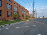 an empty street in front of a large red brick building on the other side of the road is a street light that has a line for motorists