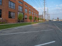 an empty street in front of a large red brick building on the other side of the road is a street light that has a line for motorists