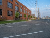 an empty street in front of a large red brick building on the other side of the road is a street light that has a line for motorists