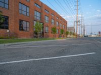 an empty street in front of a large red brick building on the other side of the road is a street light that has a line for motorists