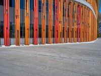 a concrete structure made into rows of orange and yellow poles are on a cement sidewalk