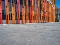 a concrete structure made into rows of orange and yellow poles are on a cement sidewalk