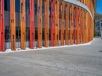 a concrete structure made into rows of orange and yellow poles are on a cement sidewalk