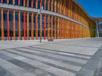 a concrete structure made into rows of orange and yellow poles are on a cement sidewalk