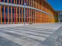 a concrete structure made into rows of orange and yellow poles are on a cement sidewalk