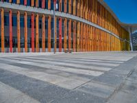 a concrete structure made into rows of orange and yellow poles are on a cement sidewalk