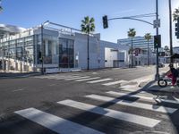 a large white building is on the corner of the street with palm trees in the background