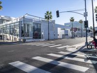 a large white building is on the corner of the street with palm trees in the background