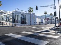 a large white building is on the corner of the street with palm trees in the background