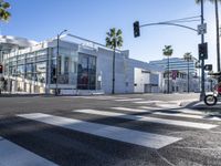 a large white building is on the corner of the street with palm trees in the background