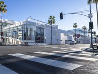 a large white building is on the corner of the street with palm trees in the background