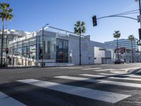 a large white building is on the corner of the street with palm trees in the background