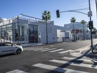 a large white building is on the corner of the street with palm trees in the background