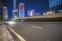 a busy city at night with the traffic passing through it and illuminated high rise buildings