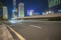 a busy city at night with the traffic passing through it and illuminated high rise buildings