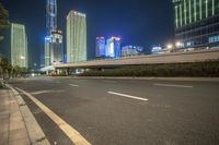 a busy city at night with the traffic passing through it and illuminated high rise buildings