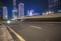 a busy city at night with the traffic passing through it and illuminated high rise buildings