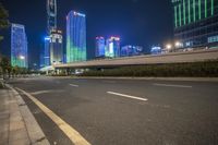 a busy city at night with the traffic passing through it and illuminated high rise buildings