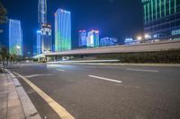 a busy city at night with the traffic passing through it and illuminated high rise buildings