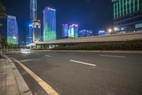 a busy city at night with the traffic passing through it and illuminated high rise buildings