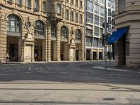 two buildings and people walking down the street next to the tram tracks is the corner of a large, busy city square