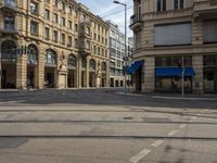 two buildings and people walking down the street next to the tram tracks is the corner of a large, busy city square