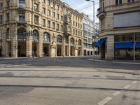 two buildings and people walking down the street next to the tram tracks is the corner of a large, busy city square