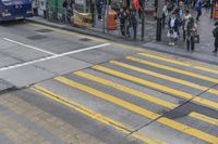 people are waiting to cross the street at an intersection on the corner of a busy sidewalk