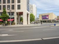 people cross an intersection near tall buildings on a busy street in a city in europe